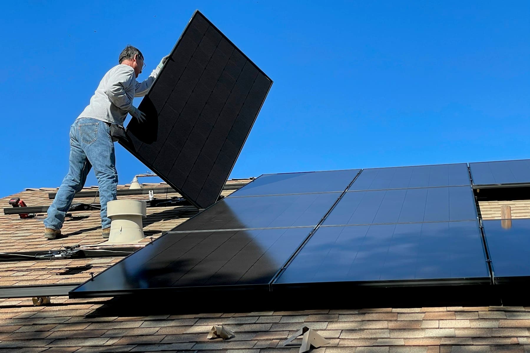 An installer fitting a solar panel to a pitched roof